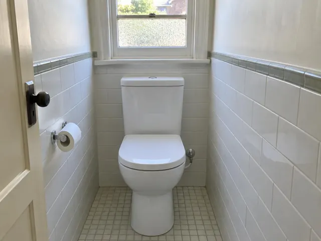 Clean white toilet in a small tiled bathroom with a window in Strathfield